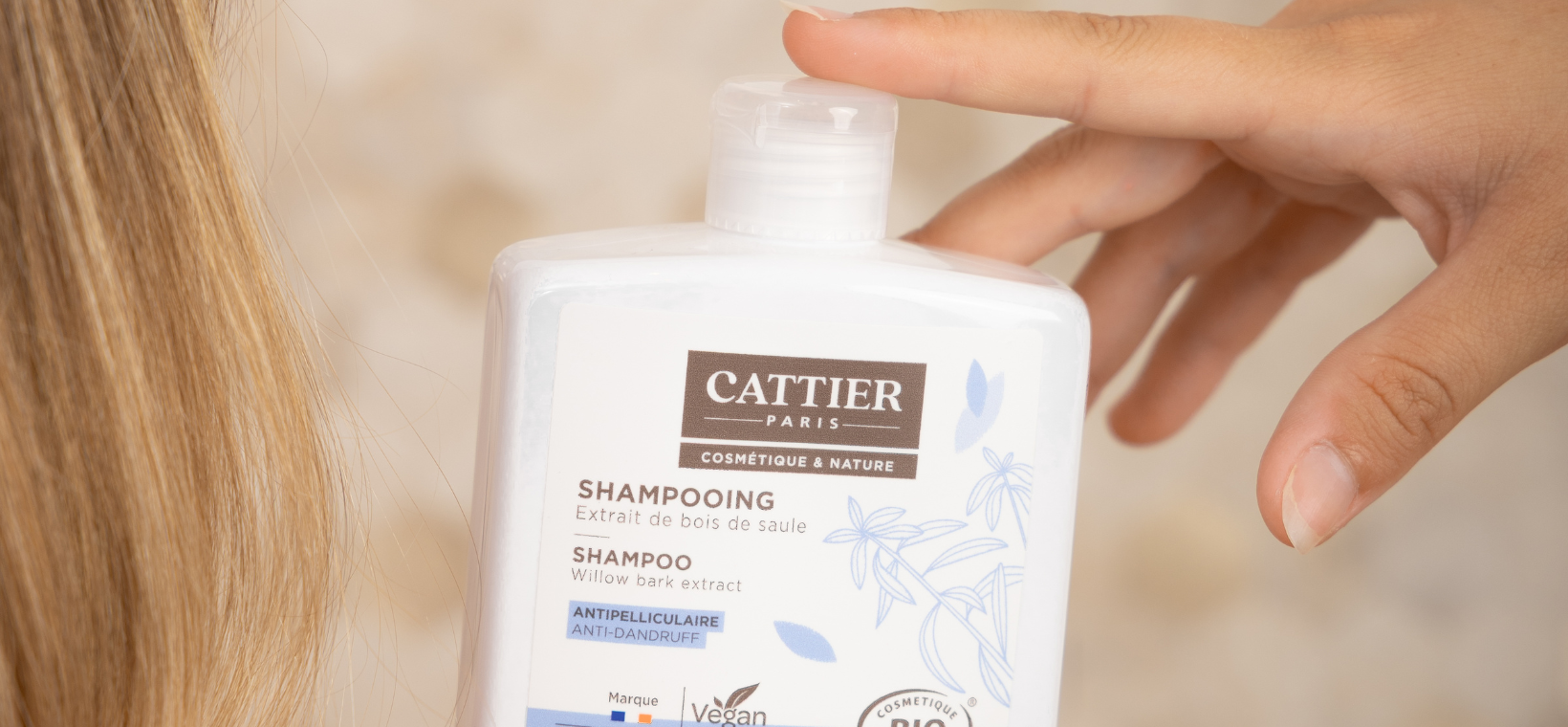 Visuel d'une femme tenant le shampoing antipelliculaire bio Cattier