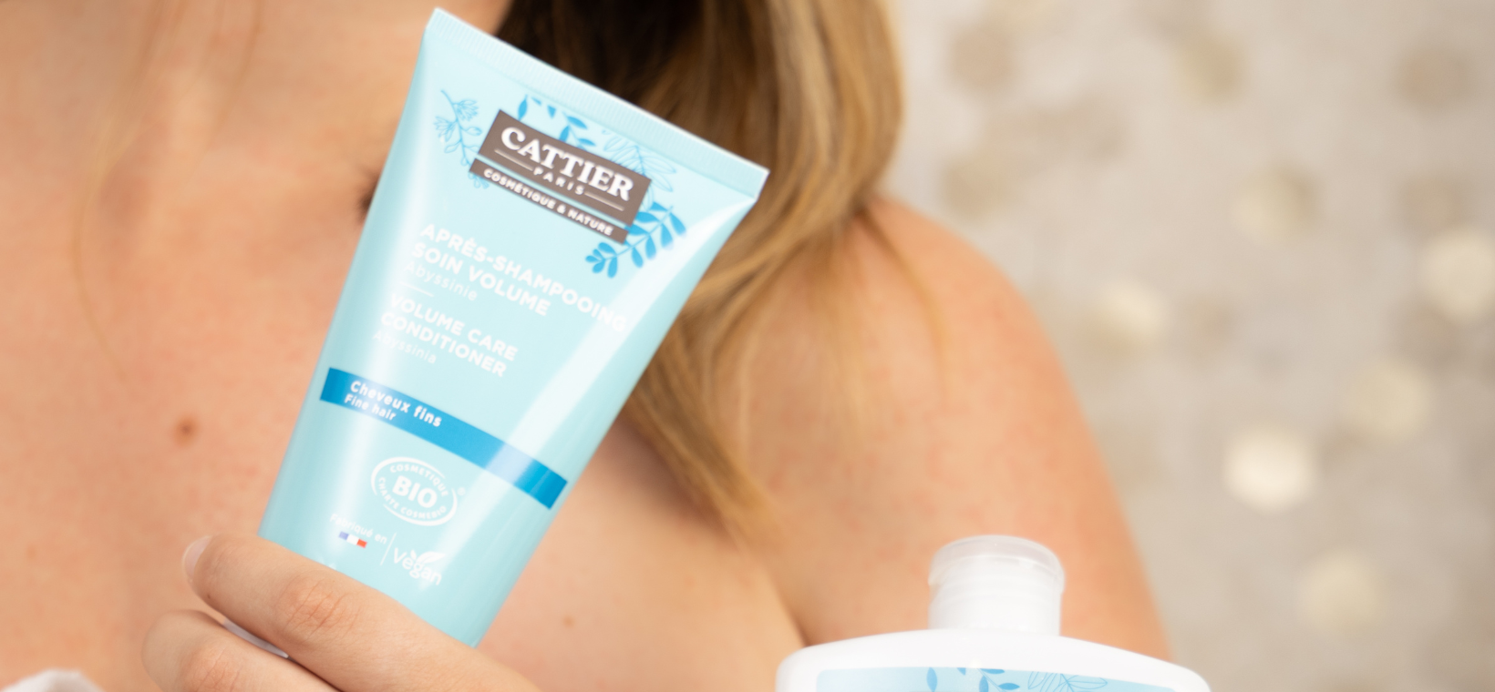 Visuel d'une femme tenant l'après-shampoing cheveux fins bio Cattier
