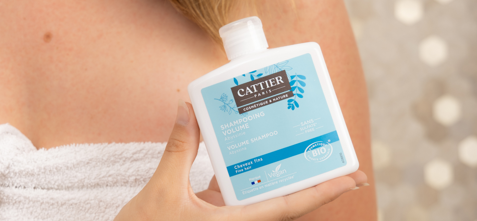 Visuel d'une femme tenant le shampoing cheveux fins bio Cattier