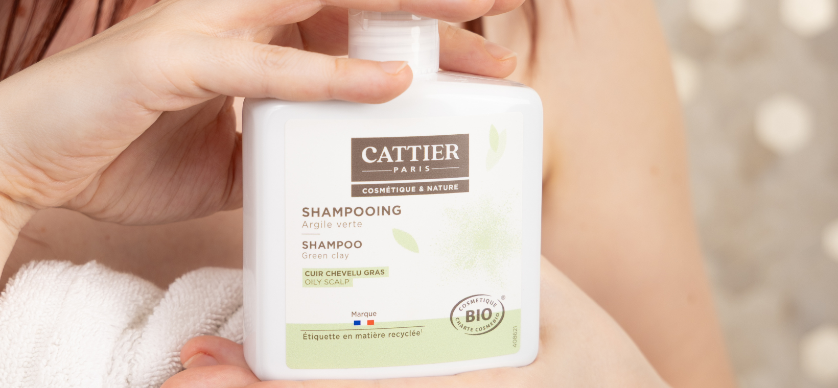 Visuel d'une femme tenant le shampoing cheveux gras bio Cattier
