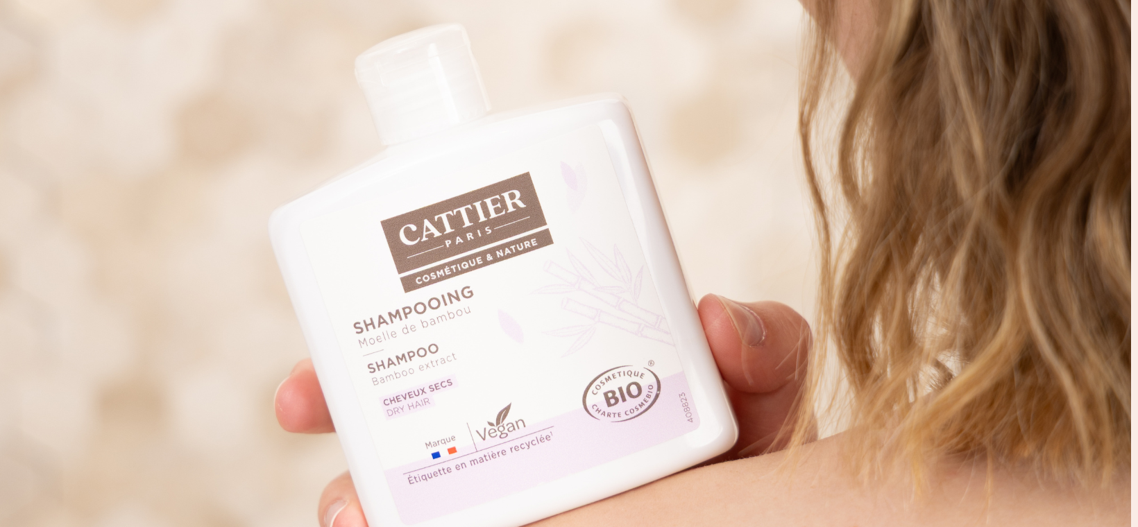 Visuel d'une femme tenant le shampoing cheveux secs bio Cattier