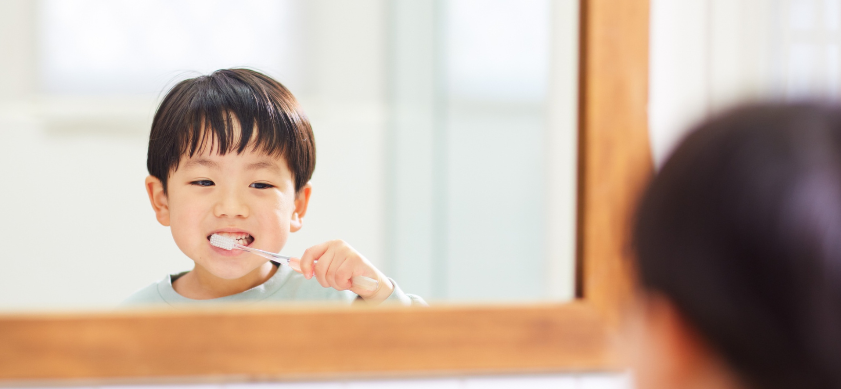 Visuel d'un enfant se brossant les dents face au miroir avec le dentifrice menthe douce bio Cattier