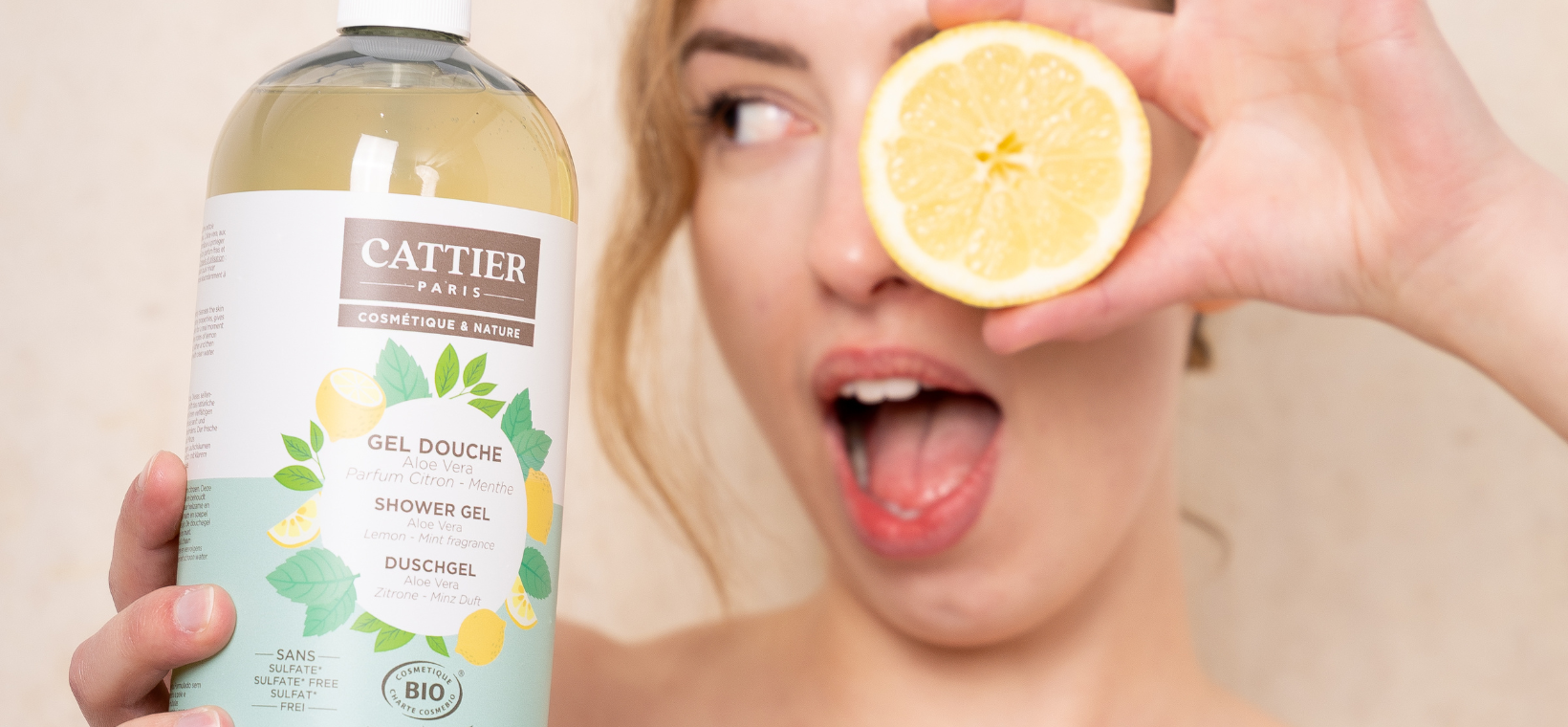 Visuel d'une femme avec le gel douche bio citron menthe Cattier avec un citron qui cache son oeil