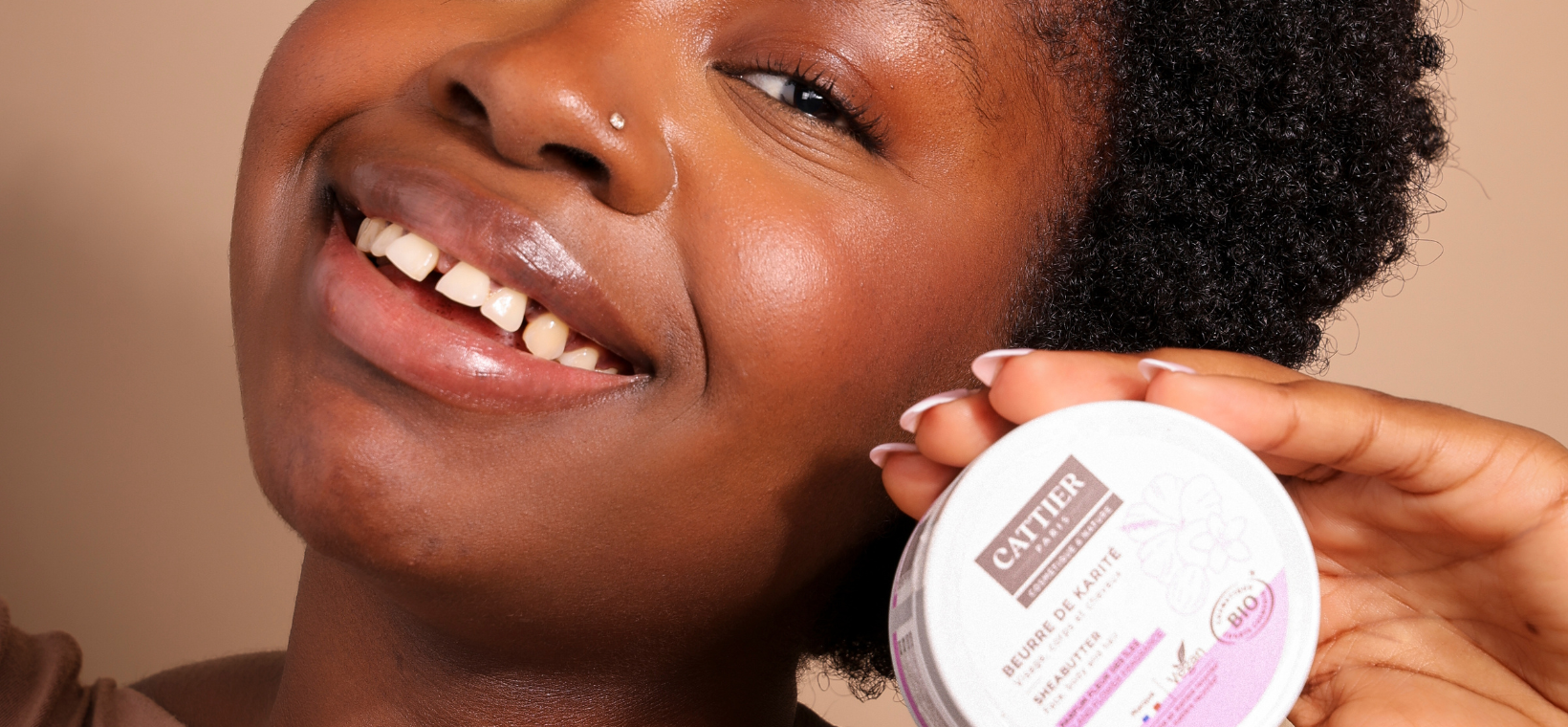 Visuel d'une femme souriante tenant à la main le beurre de karité fleur des îles