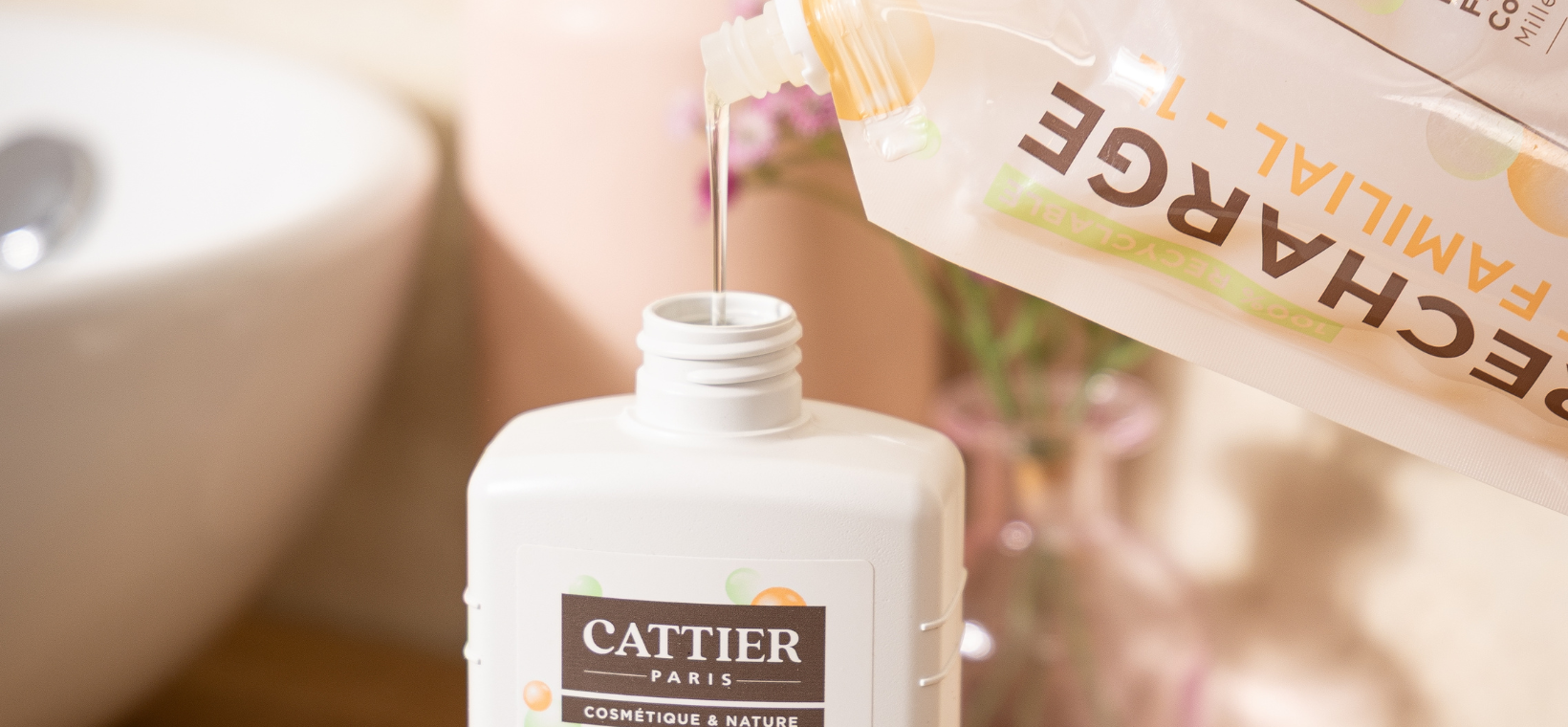 Visuel d'une personne rechargeant le moussant familial fleur d'oranger dans le contenant de base