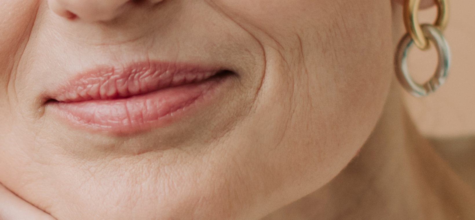 Visuel du sourire d'une femme d'âge mur utilisant le soin lèvres anti-âge lissant Cattier
