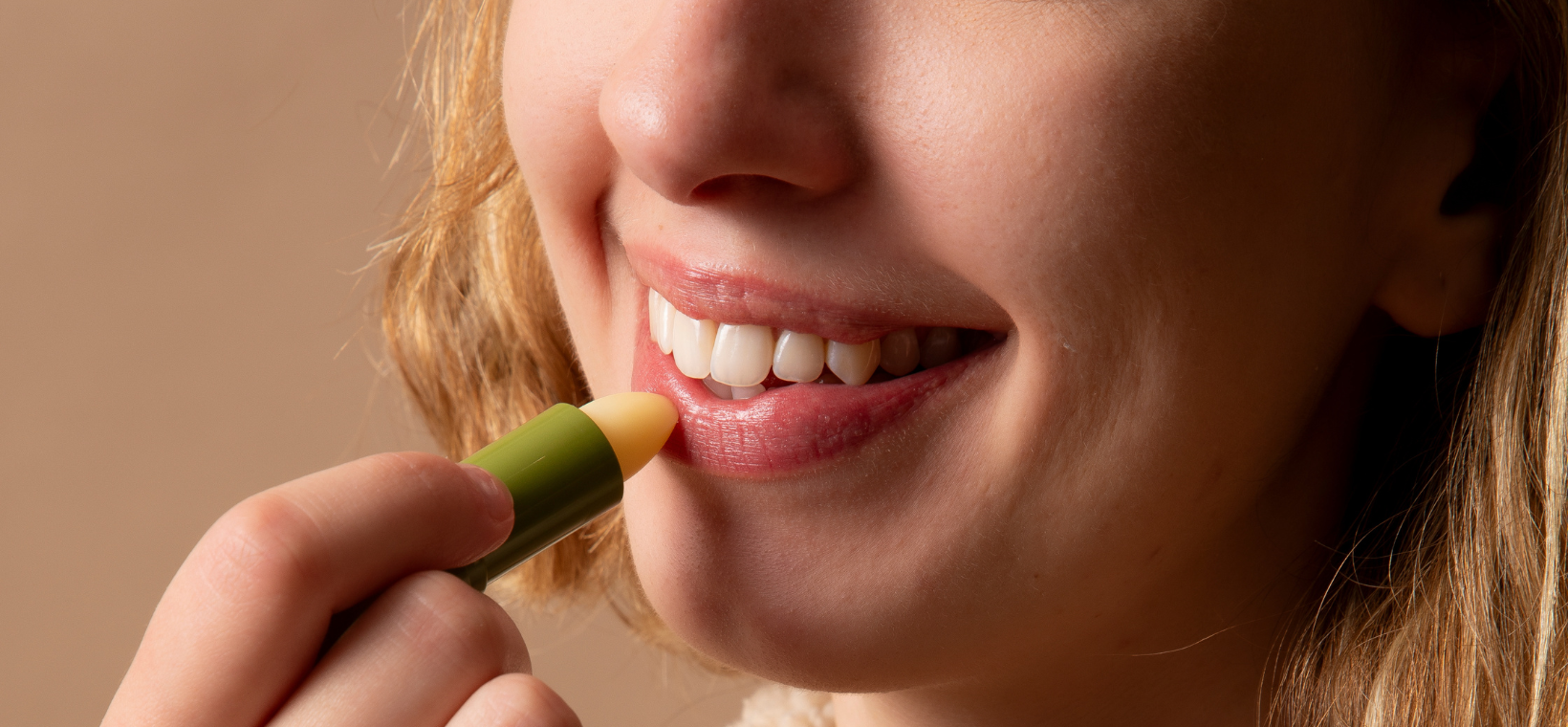 Visuel d'une femme s'appliquant du soin lèvres stick Cattier en souriant